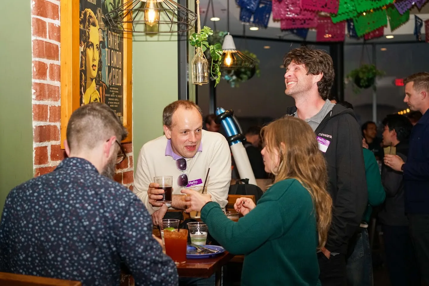Attendees chatting around a table by the brick wall