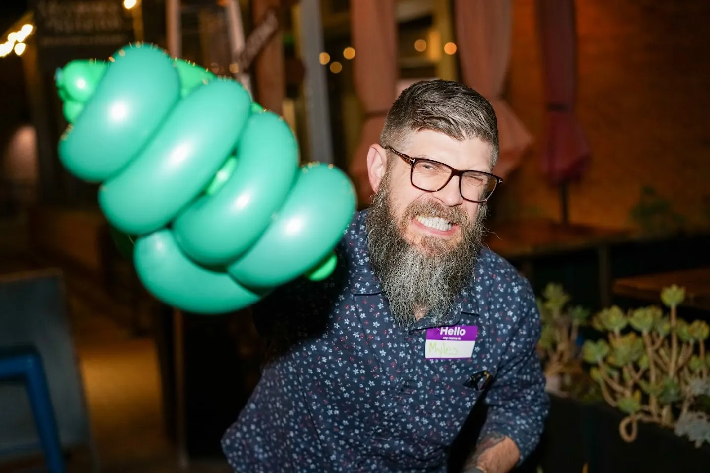 Guest holding a green balloon sculpture toward the camera