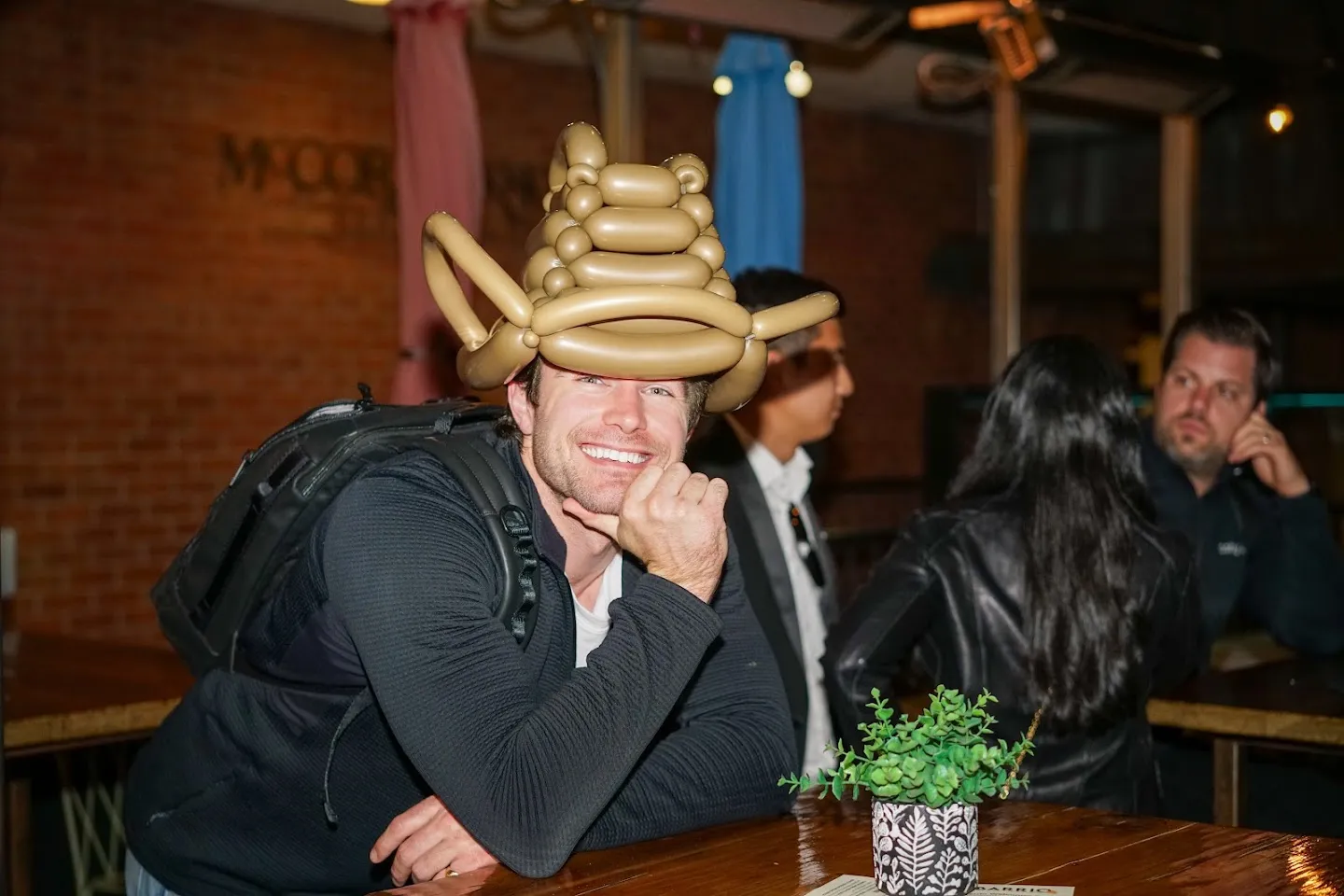 Guest in a gold balloon hat leaning toward the camera