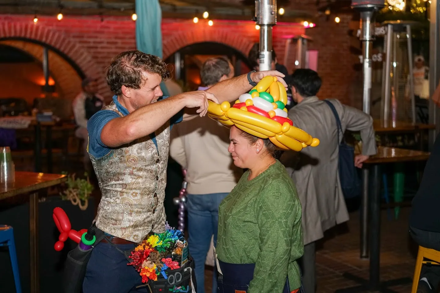 Balloon artist fitting a colorful hat on a guest