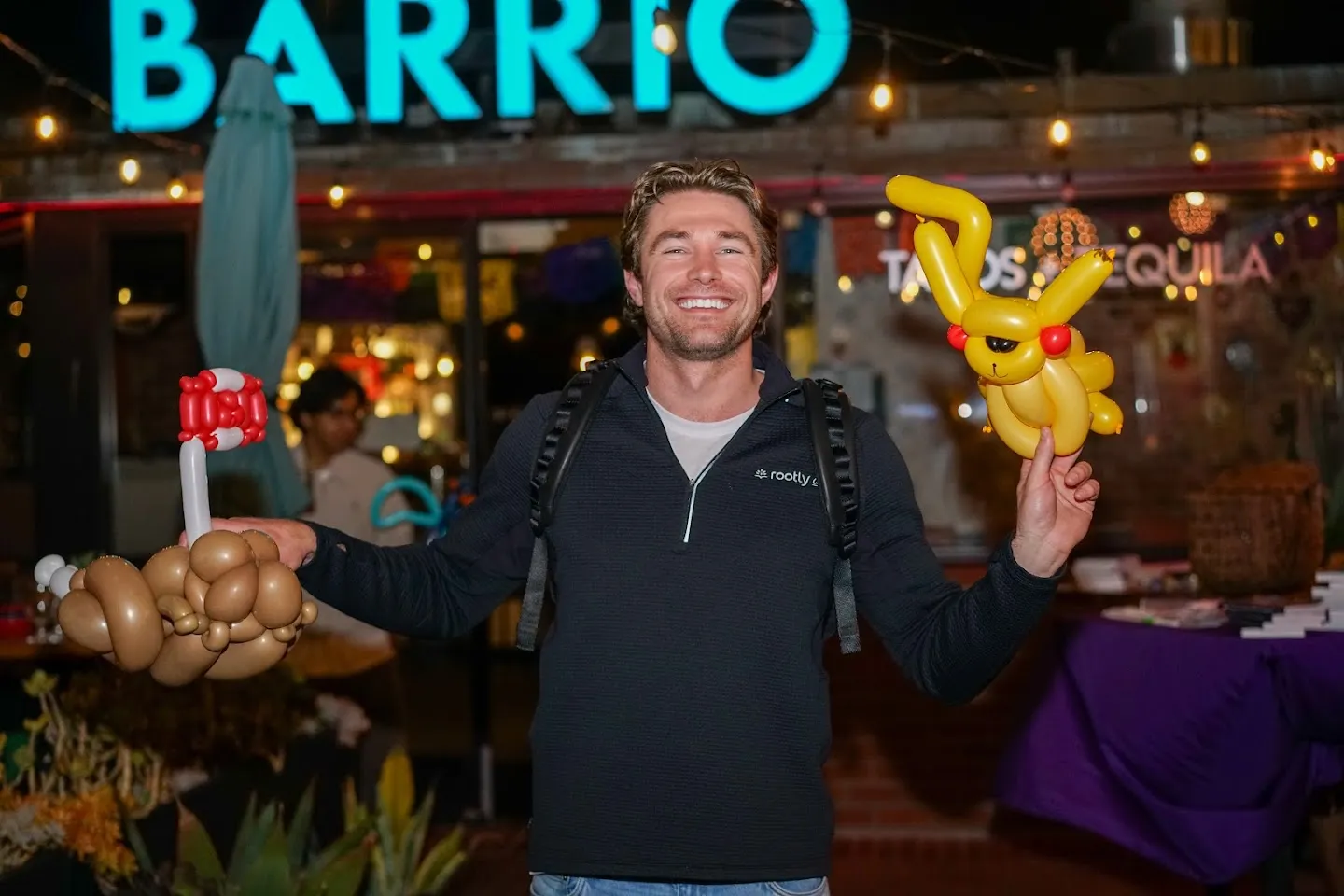 Guest posing beneath the illuminated Barrio sign with balloons
