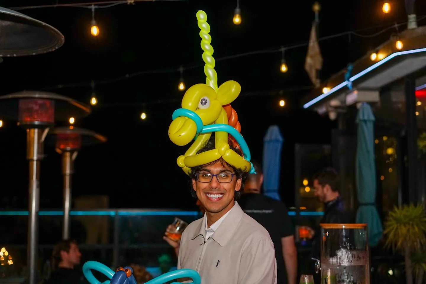 Guest wearing a tall yellow and green balloon hat