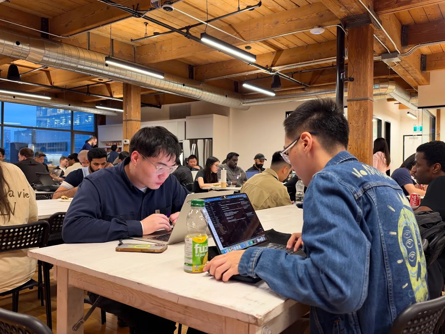 Builders working on laptops around shared tables at the AI agents workshop