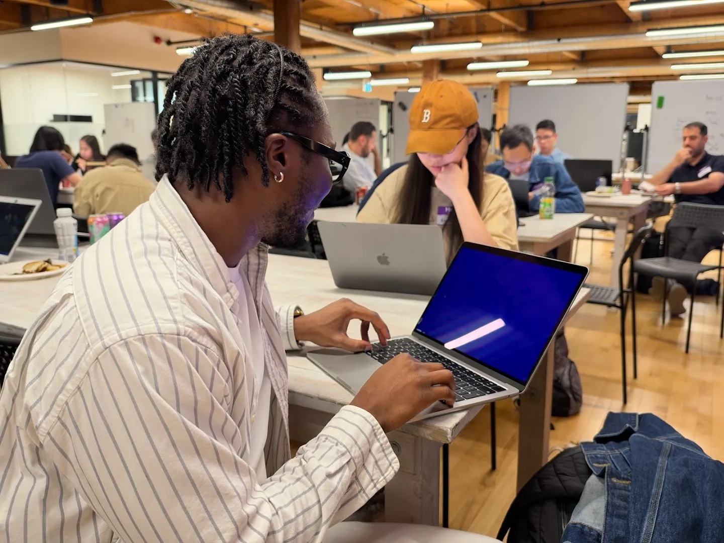 Builders working on laptops around shared tables at the AI agents workshop