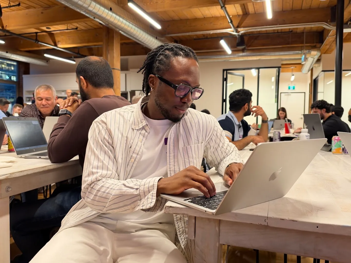 Builders working on laptops around shared tables at the AI agents workshop