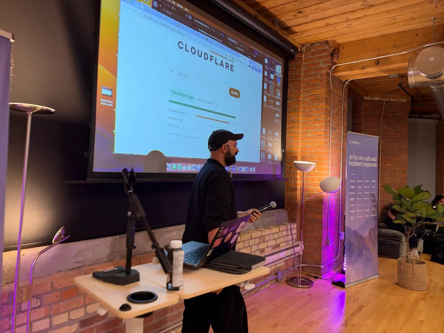 A builder presenting a project from a laptop beneath the projection screen