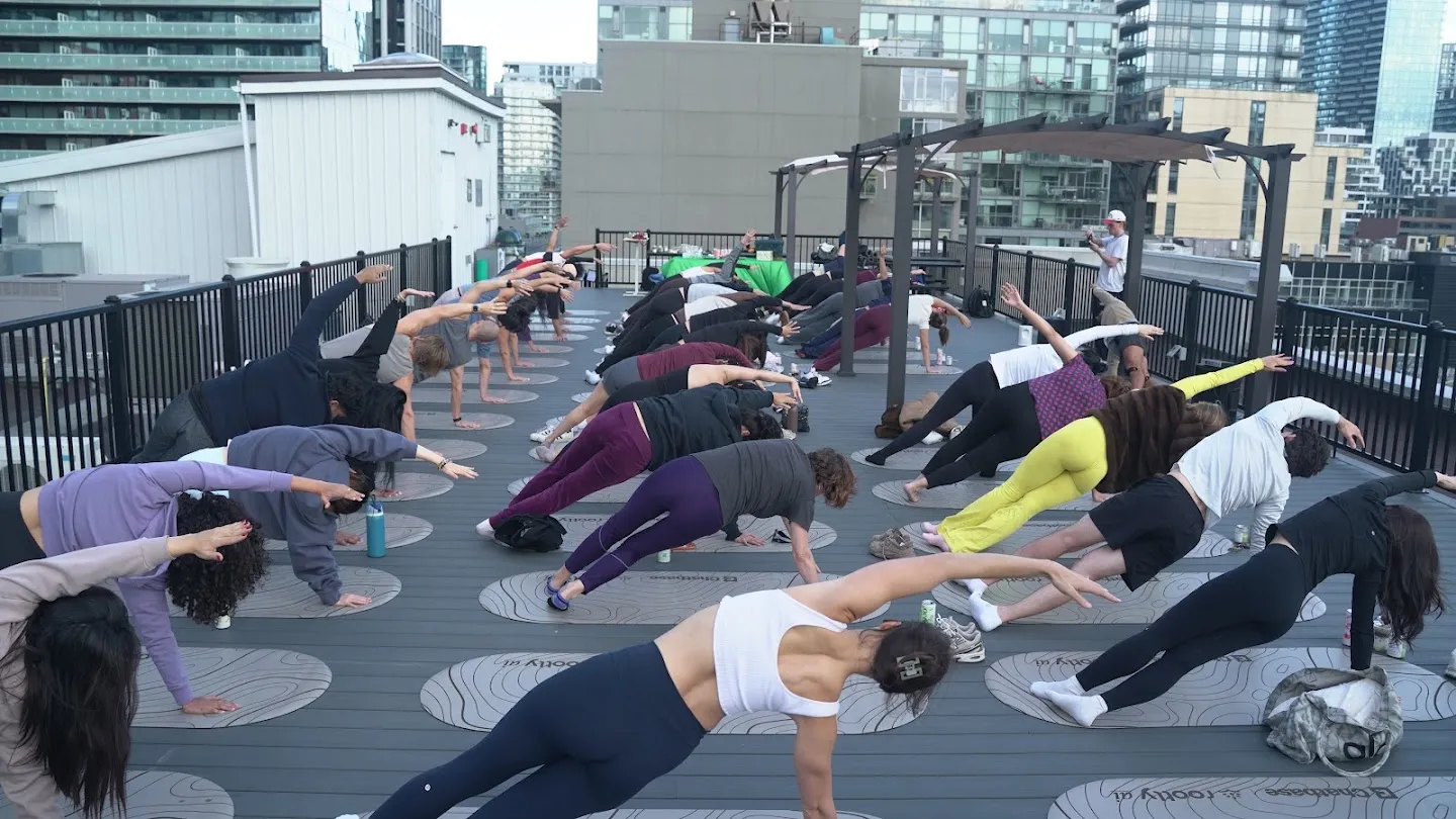 Participants stretching through standing yoga poses against the Toronto skyline