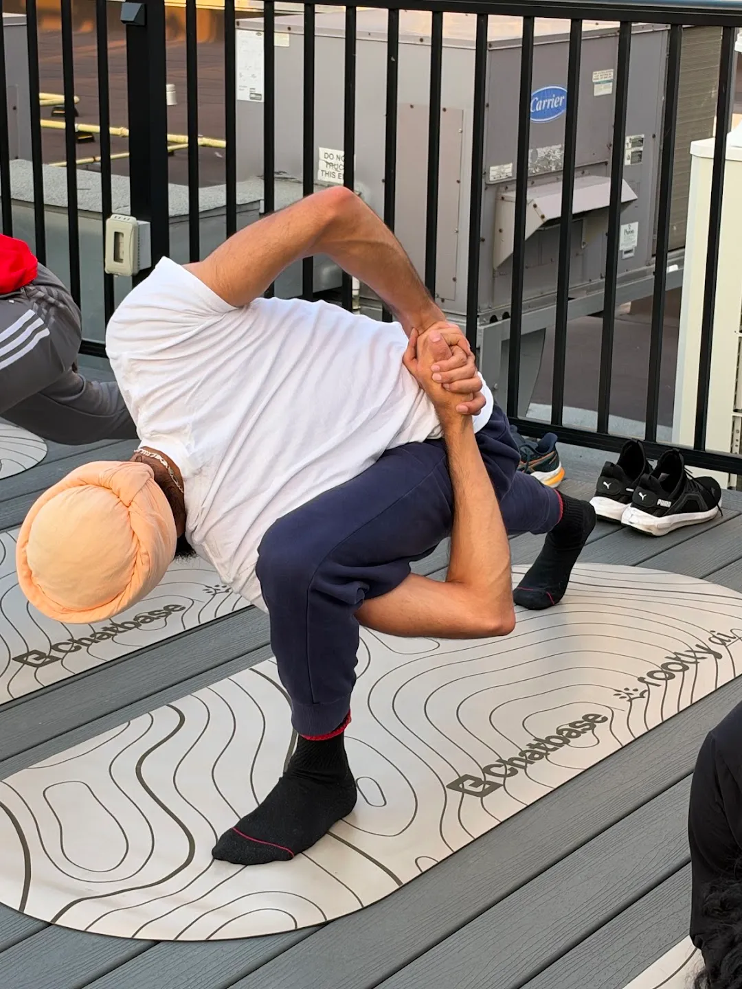 A participant stretching on a mat beside the rooftop railing