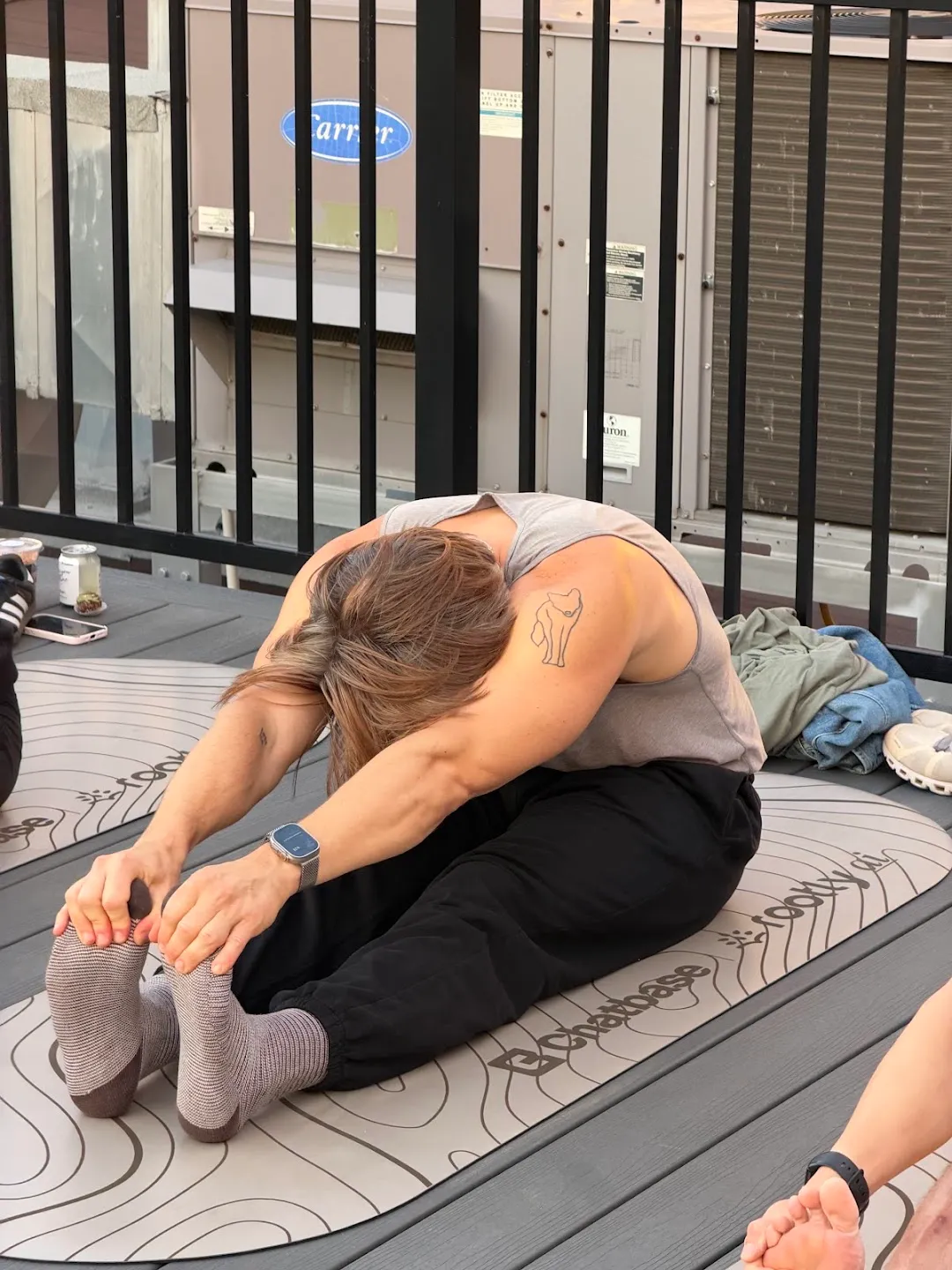A participant stretching on a mat beside the rooftop railing