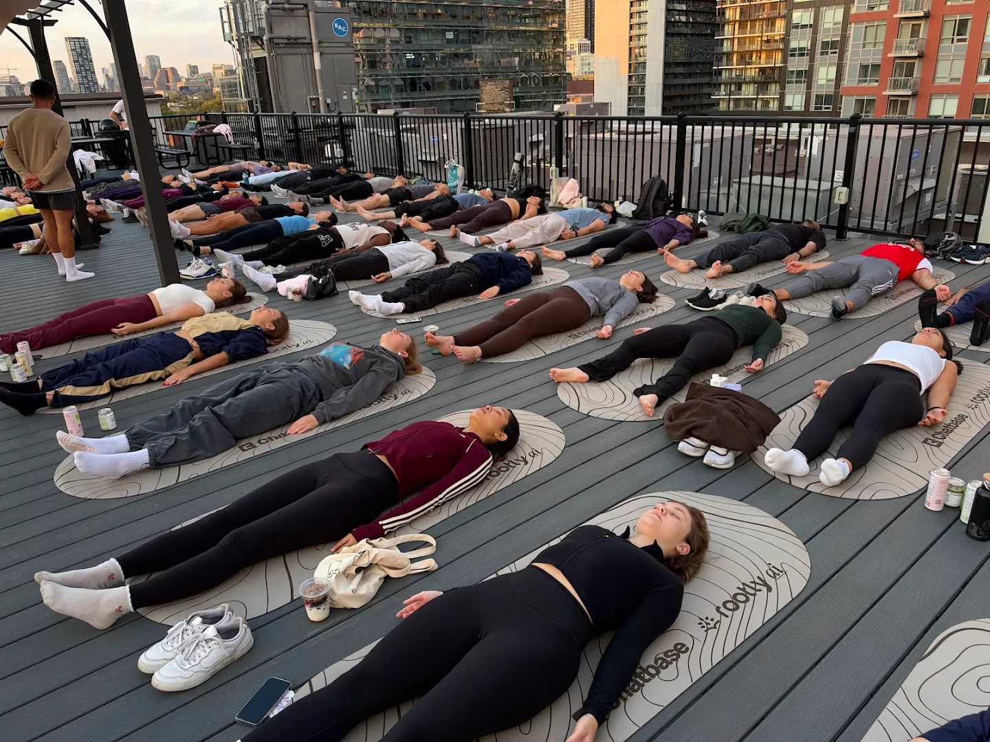 The yoga class resting on mats on the rooftop deck