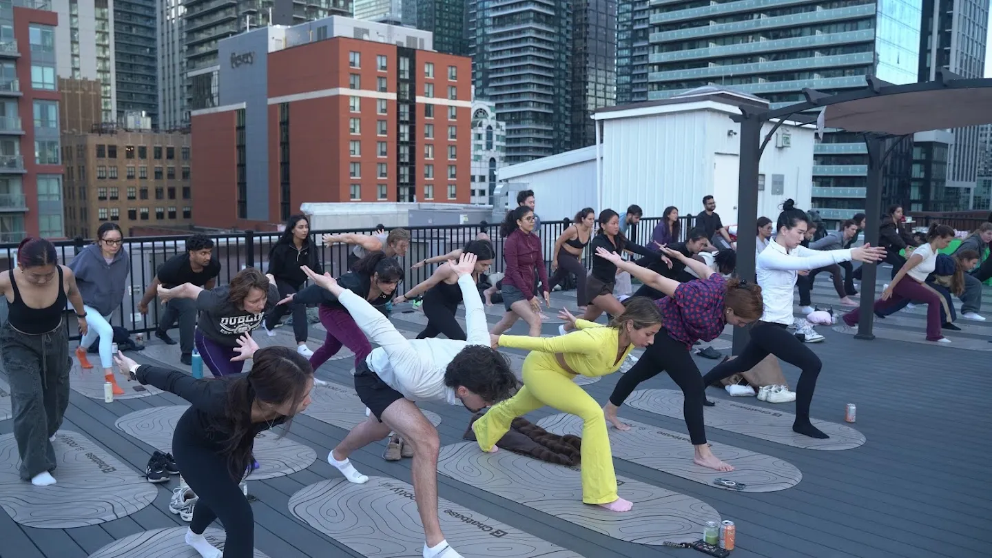 Participants stretching through standing yoga poses against the Toronto skyline