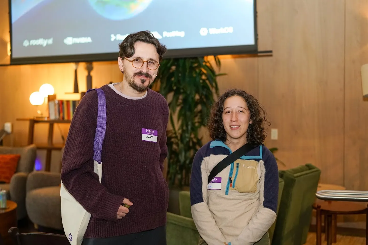 Two guests posing beneath the event screen
