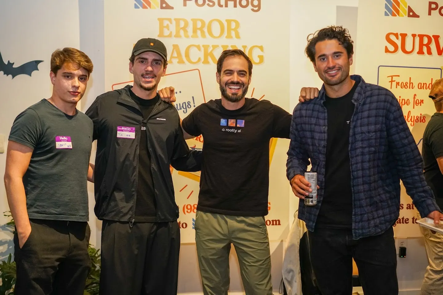 Four guests posing beside PostHog posters