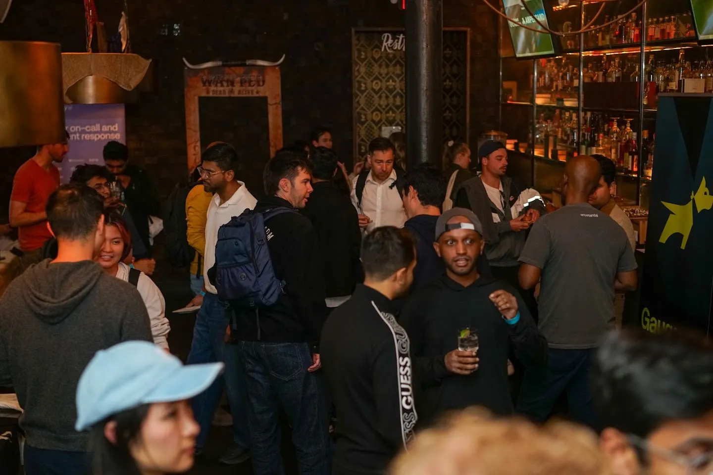 Guests talking around the bar and library shelves at Novela