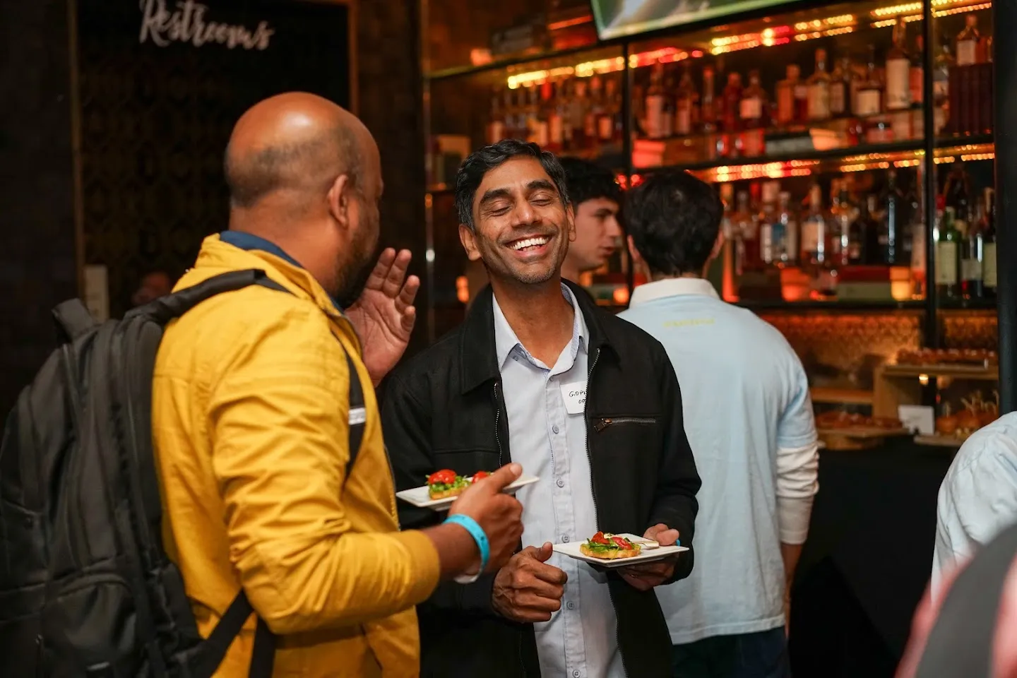 Guests talking around the bar and library shelves at Novela