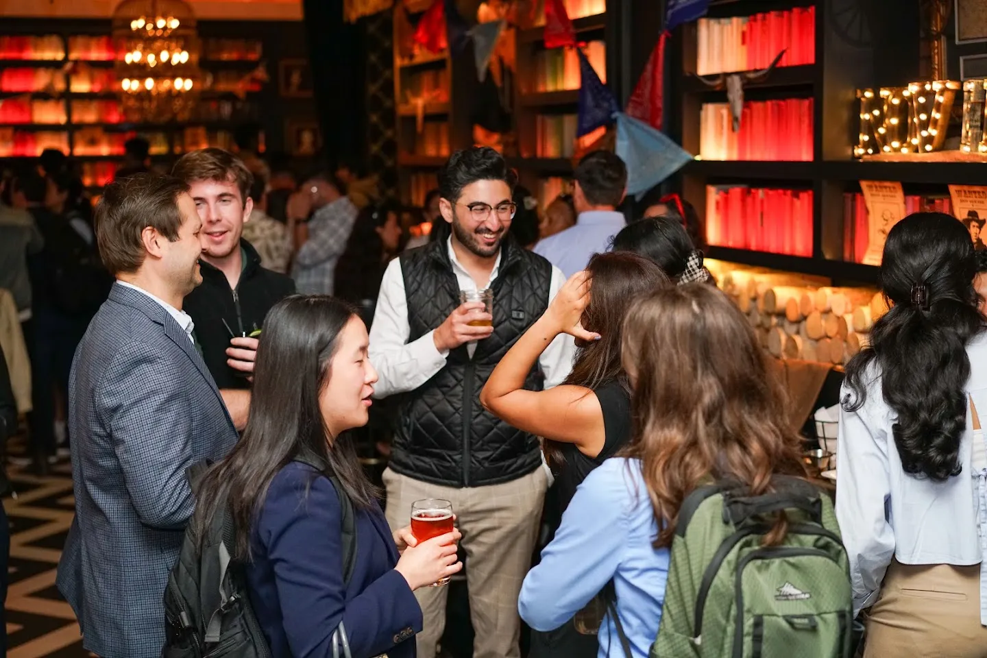 Guests talking around the bar and library shelves at Novela
